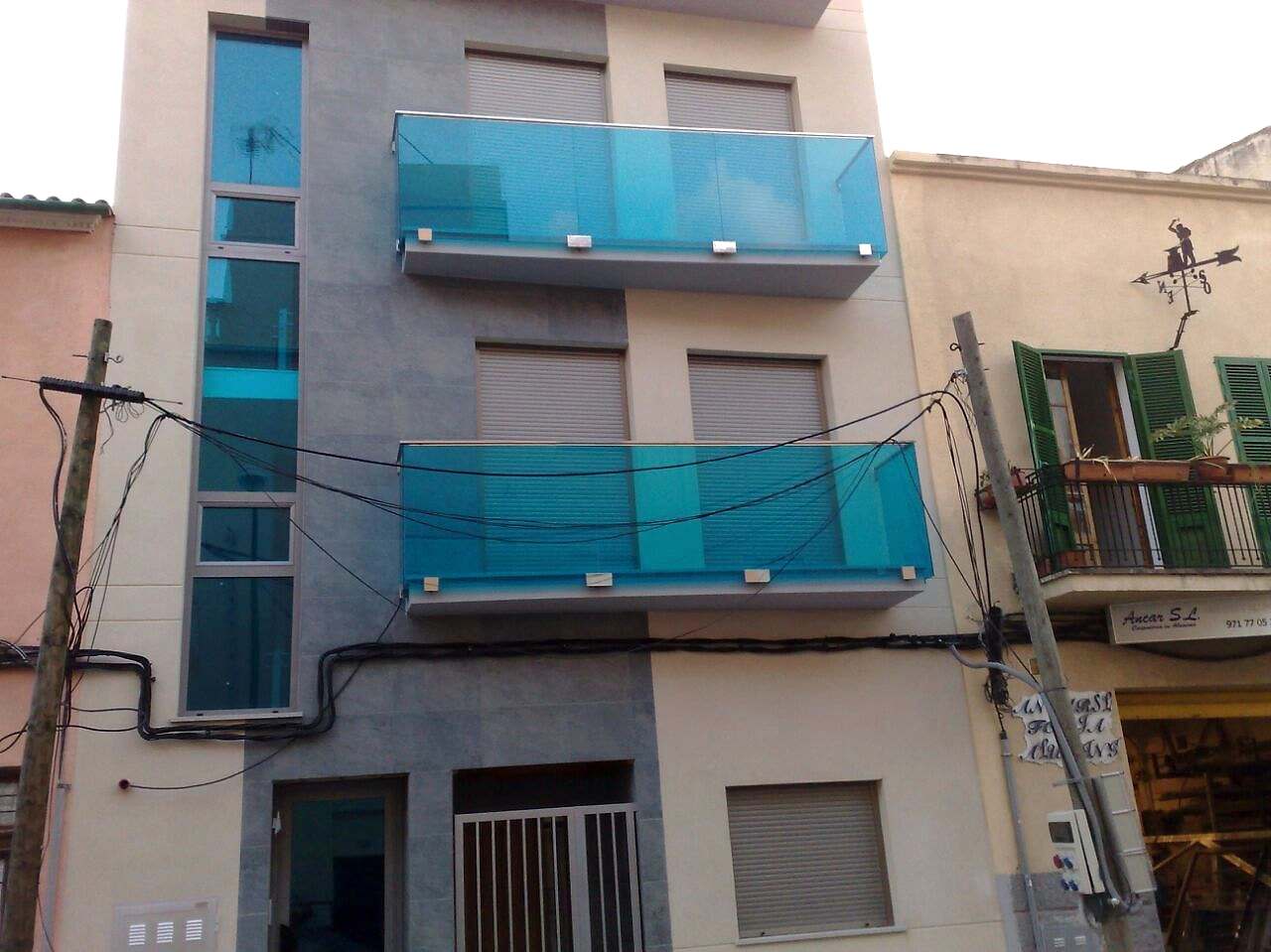 Fachada de un edificio de viviendas con balcones de vidrio en dos plantas
