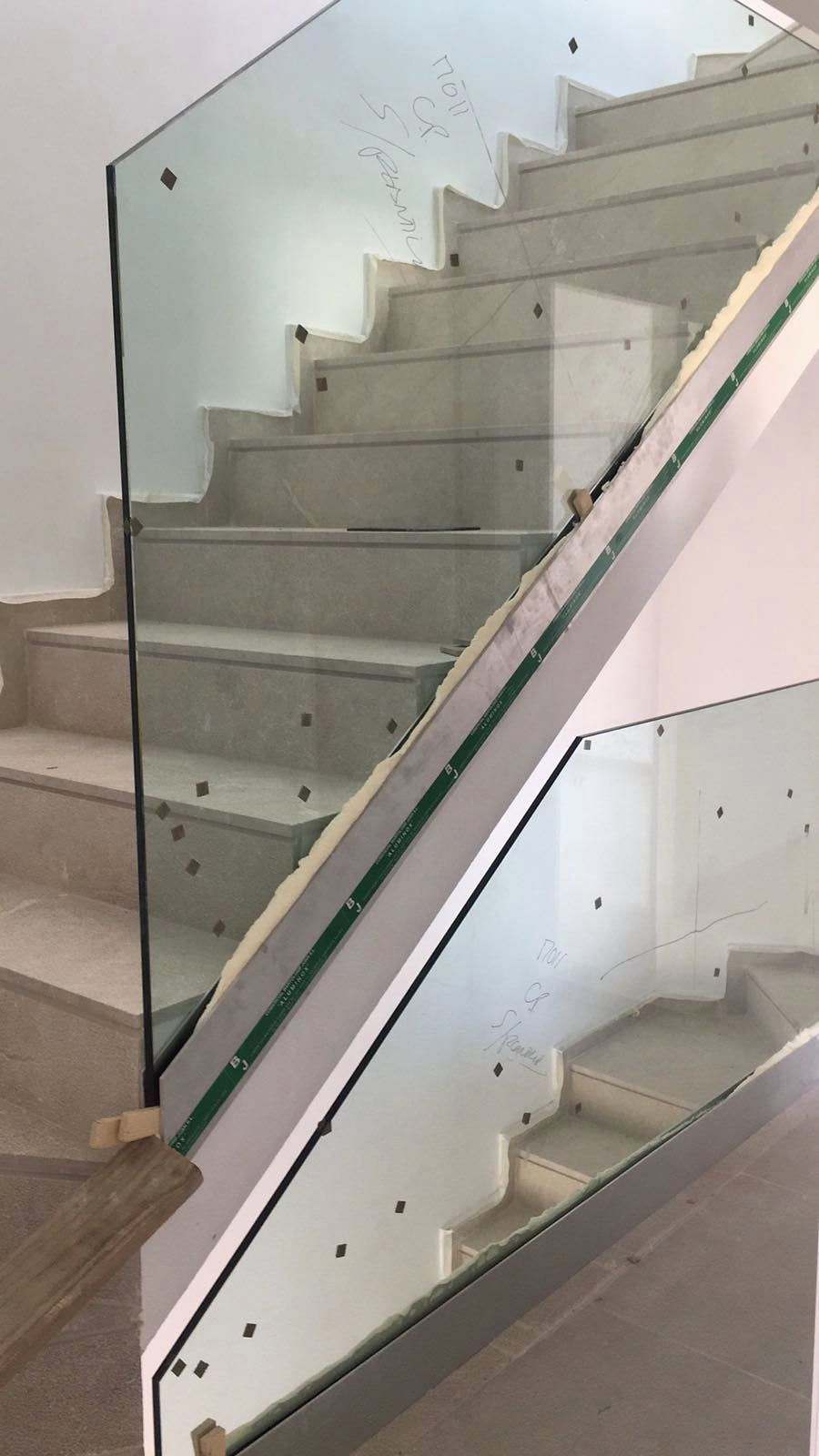 Escalera de piedra clara con dos tramos de barandilla de vidrio