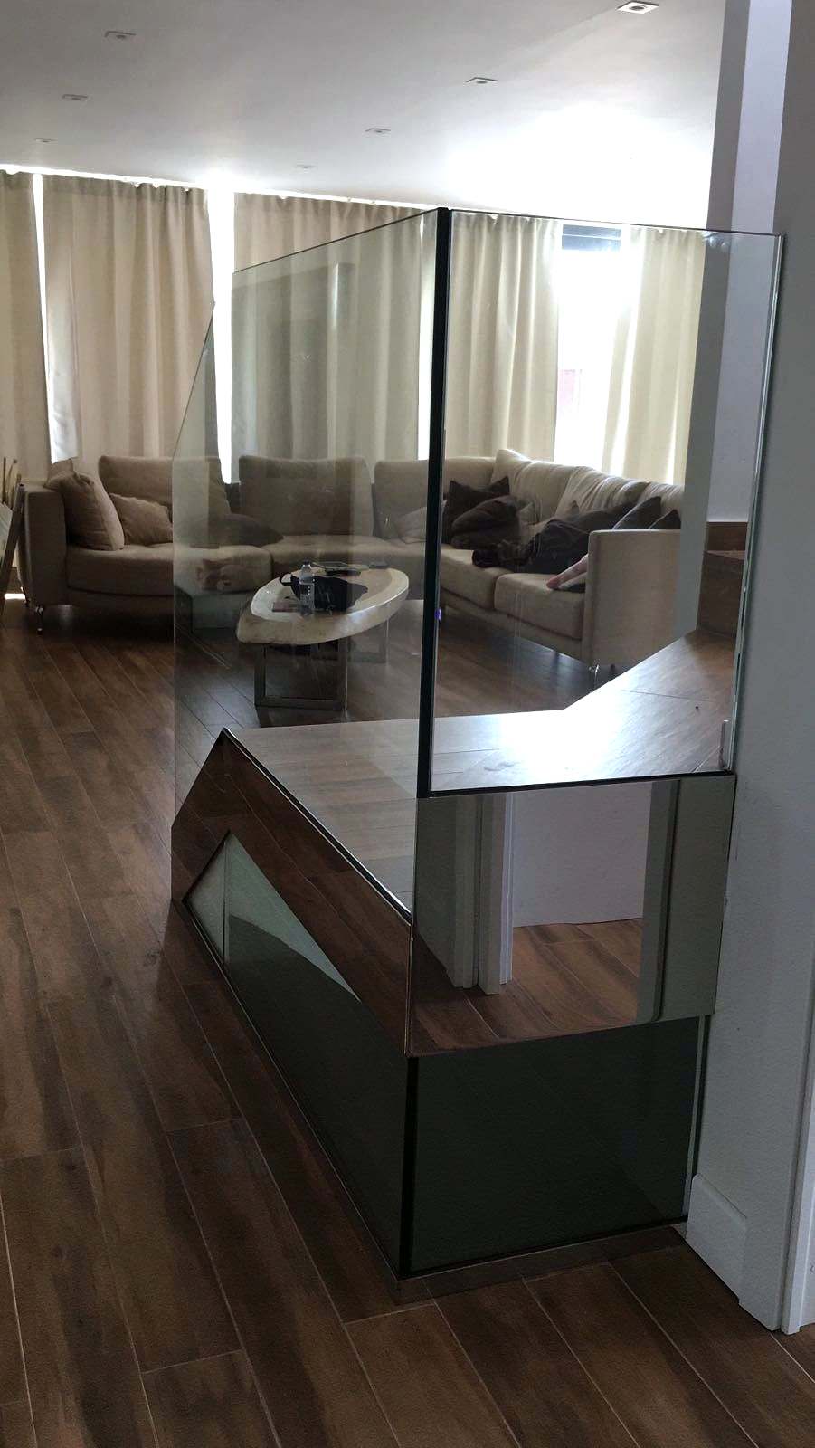 Salón visto a través de la barandilla de vidrio de un hueco de escalera