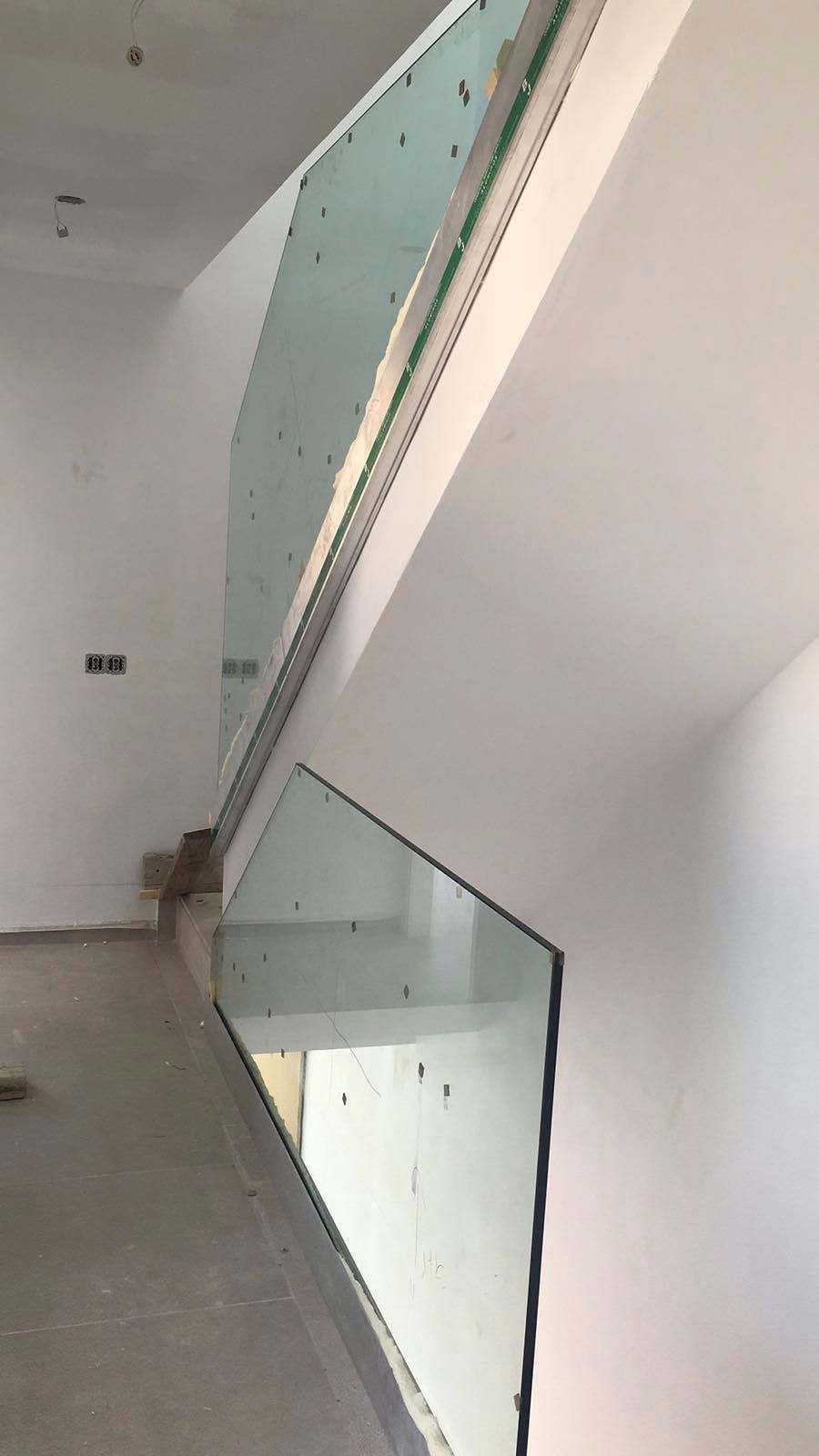 Tramo de escalera blanco con paneles de vidrio fijados al canto del forjado