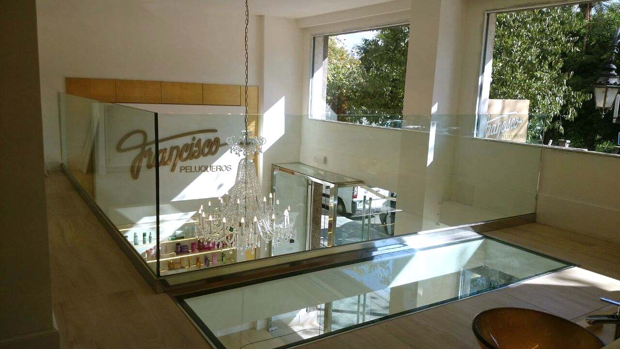 Suelo de vidrio pisable en un local, rodeado por una barandilla de vidrio