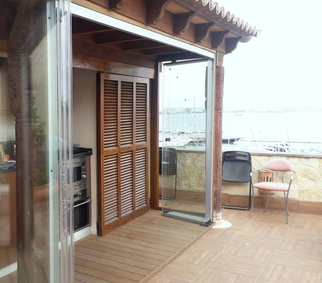 Hojas de vidrio plegables recogidas a un lado, abriendo la cocina a la terraza