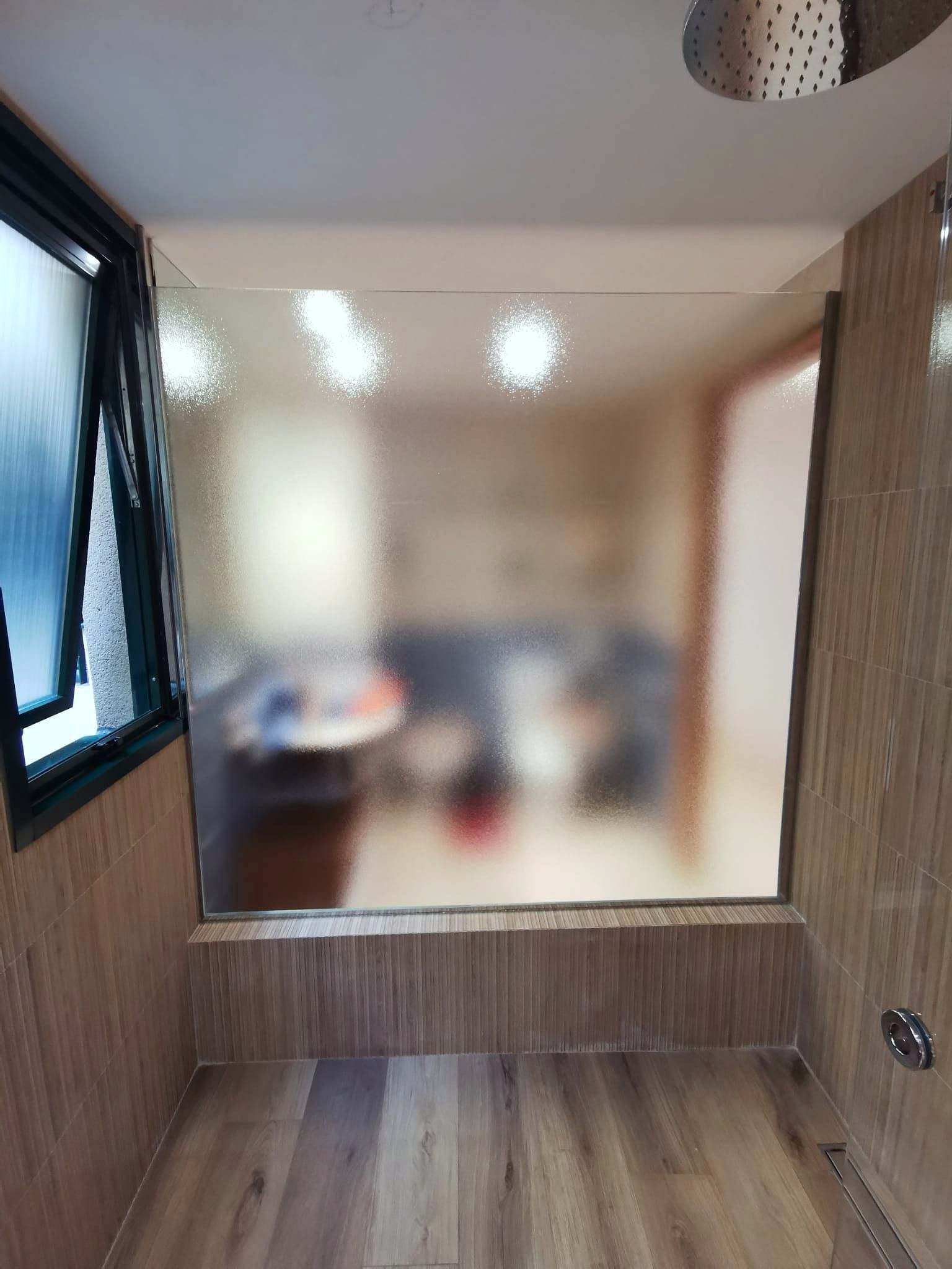 Baño separado del dormitorio por un vidrio impreso translúcido que difumina la vista