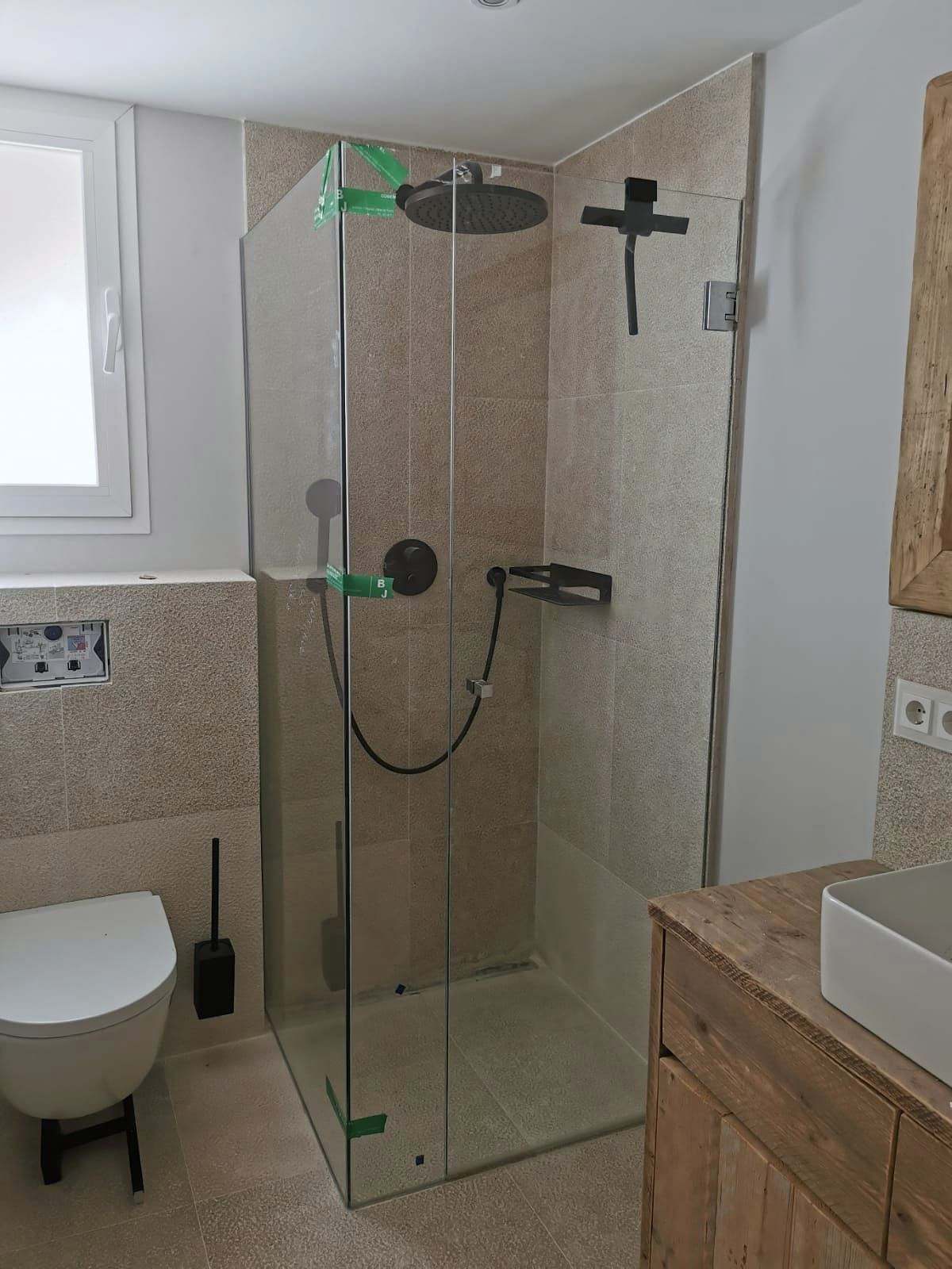 Ducha con grifería negra y mampara angular de vidrio transparente