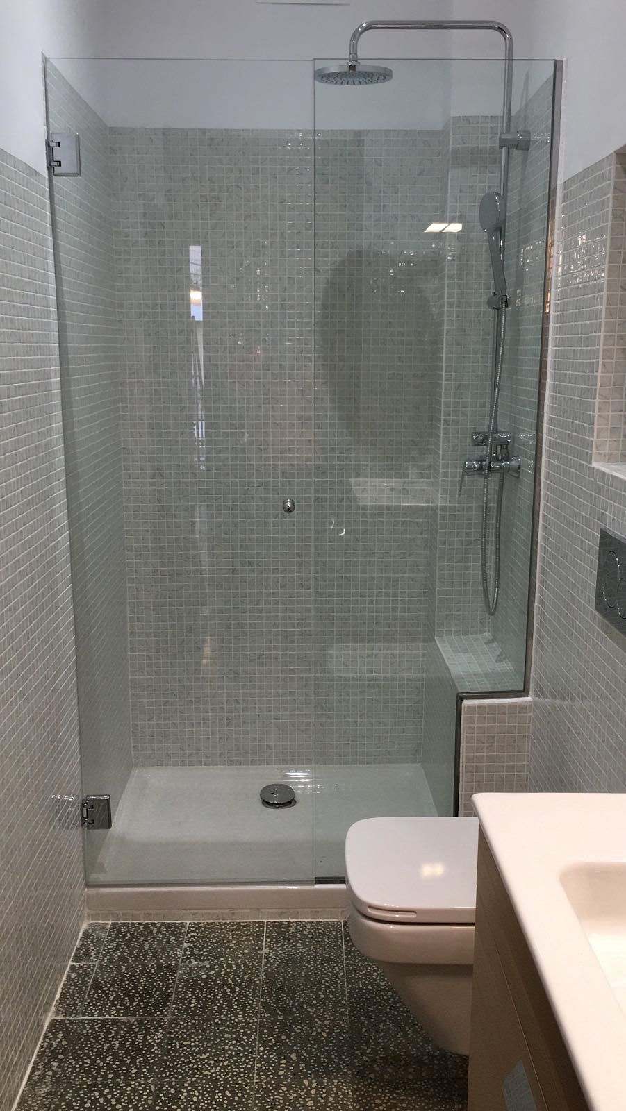 Ducha estrecha con mampara frontal de vidrio y suelo de cantos rodados