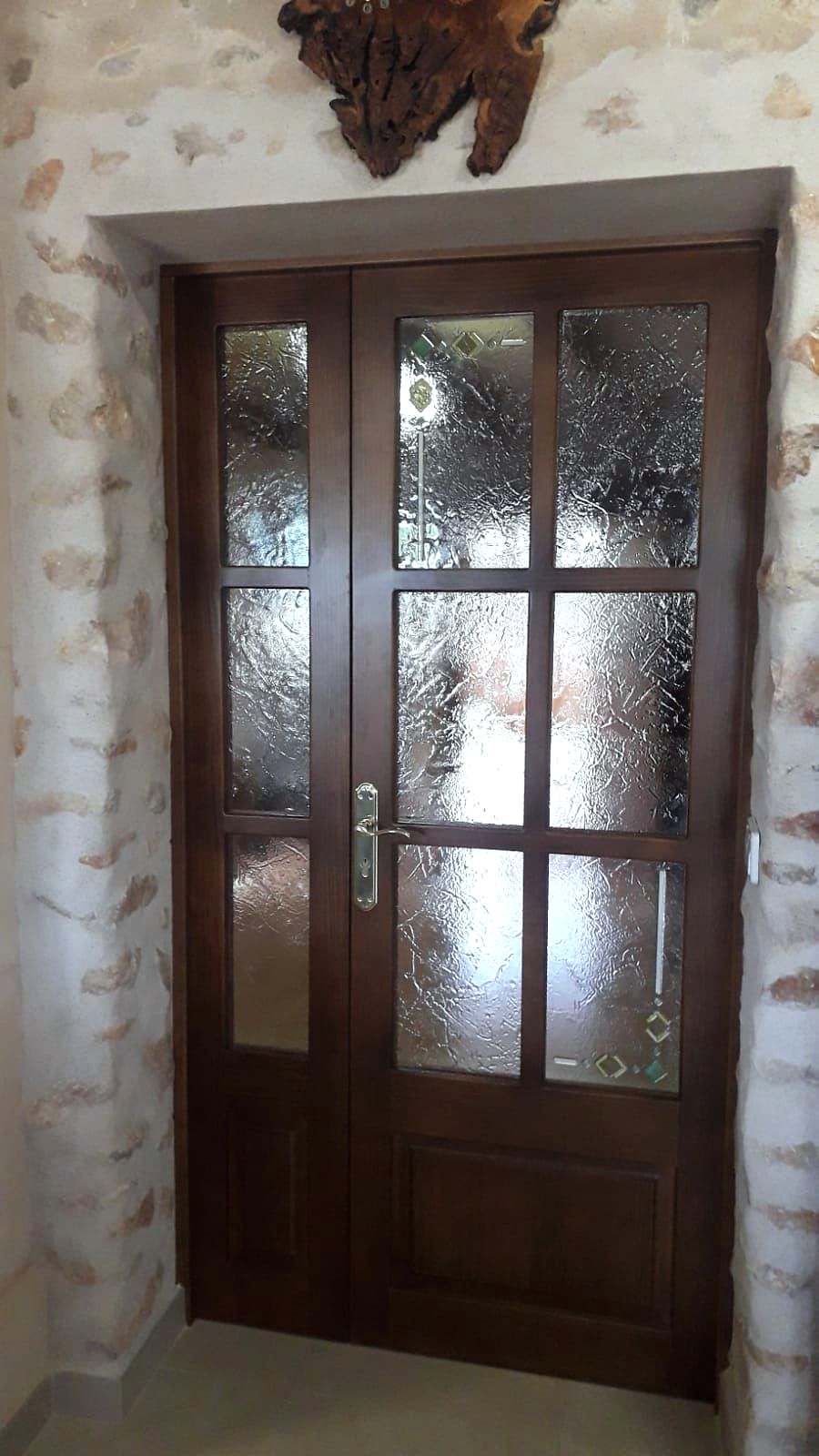 Puerta doble de madera oscura con cuarterones de vidrio fusing texturizado